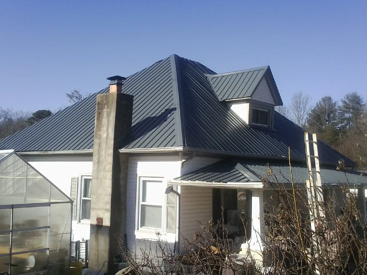 Dark blue standing seam metal roof on a white farmhouse with dormer — Slate & Tile Roof Repair by Roofing Brothers in Erlanger