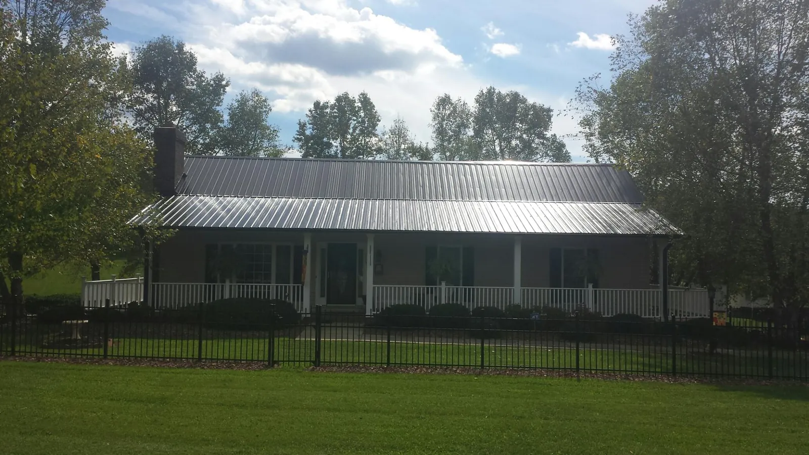 Gray metal roof on a brick ranch with a full width front porch — Gutter Guard Installation work by our crew in Erlanger