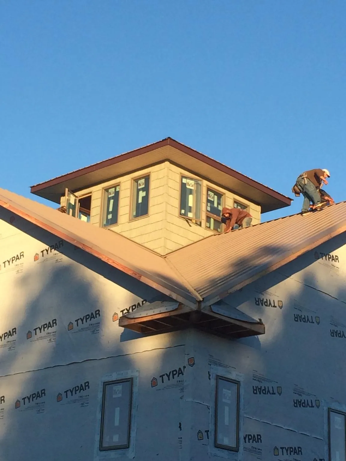 Roofers working around a rooftop cupola on a new metal roof at sunset — Roof Waterproofing in Erlanger by Roofing Brothers